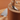 Close-up of WÜSTHOF AMICI knives standing in the round tan block, with a knife on a wooden board behind