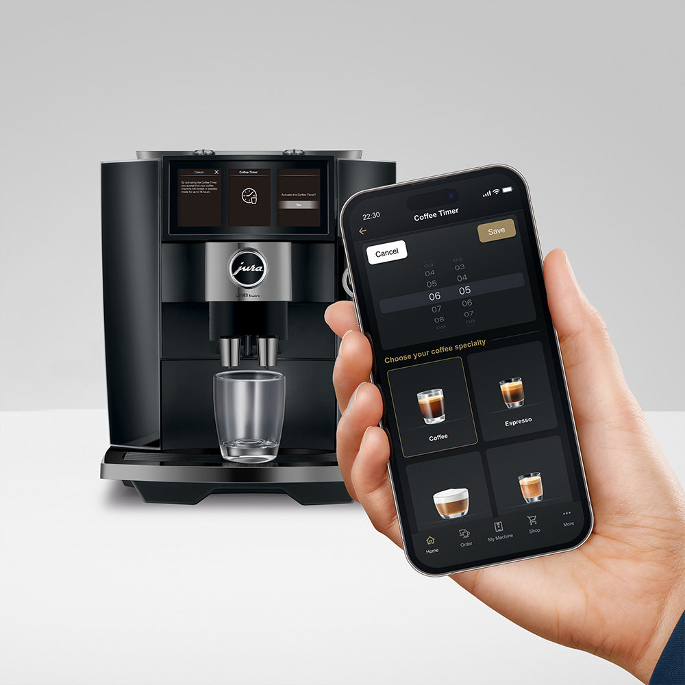 Jura J10 twin in Diamond Black, on a gray background, with the J.O.E. app on a phone
