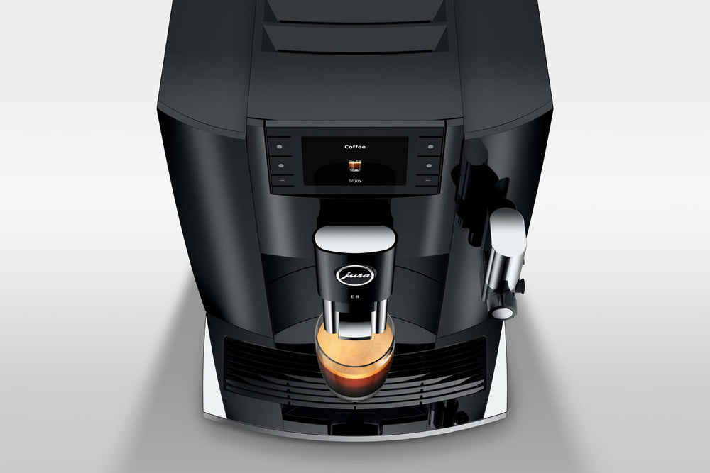 Jura E8 (4th generation) in Piano Black, close-up on a gray background, coffee spout over a cup