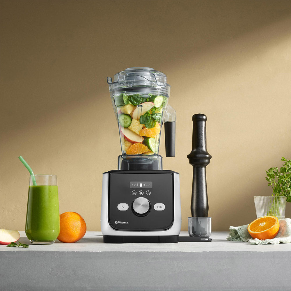 Vitamix Ascent X5 Blender in Polar White with a green smoothie, oranges and the tamper