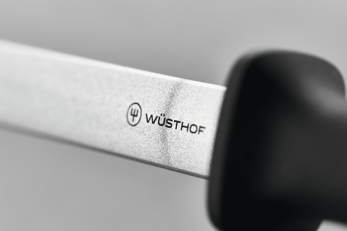 Close-up of the WÜSTHOF logo on the wide diamond steel where it meets the black handle