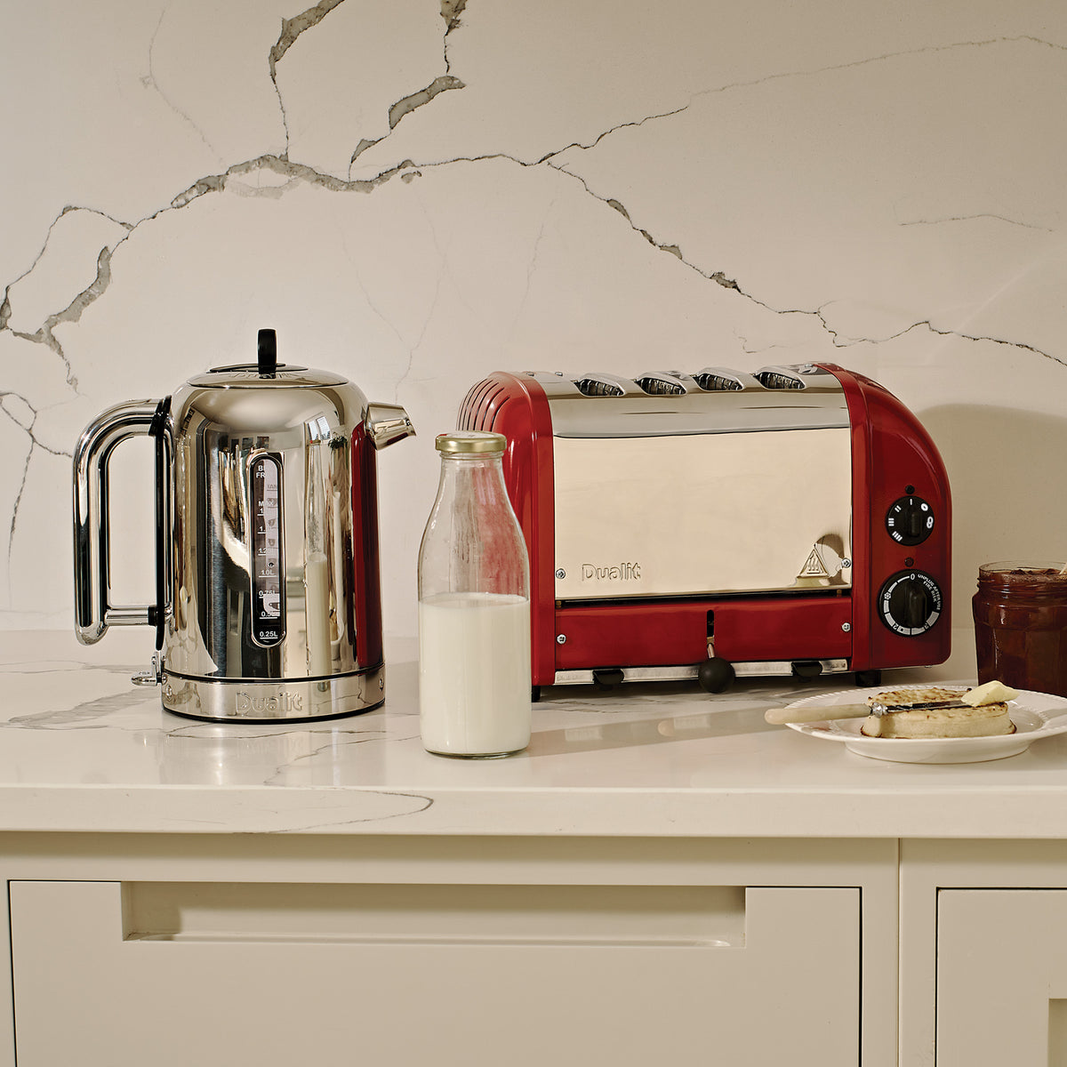Dualit Classic 4-slice toaster in red beside a Dualit Classic kettle and a bottle of milk on a marble counter