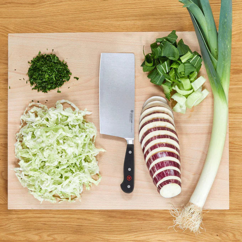 WÜSTHOF CLASSIC 7" Chinese Chef's Knife on a board with shredded cabbage, sliced aubergine, leek and herbs