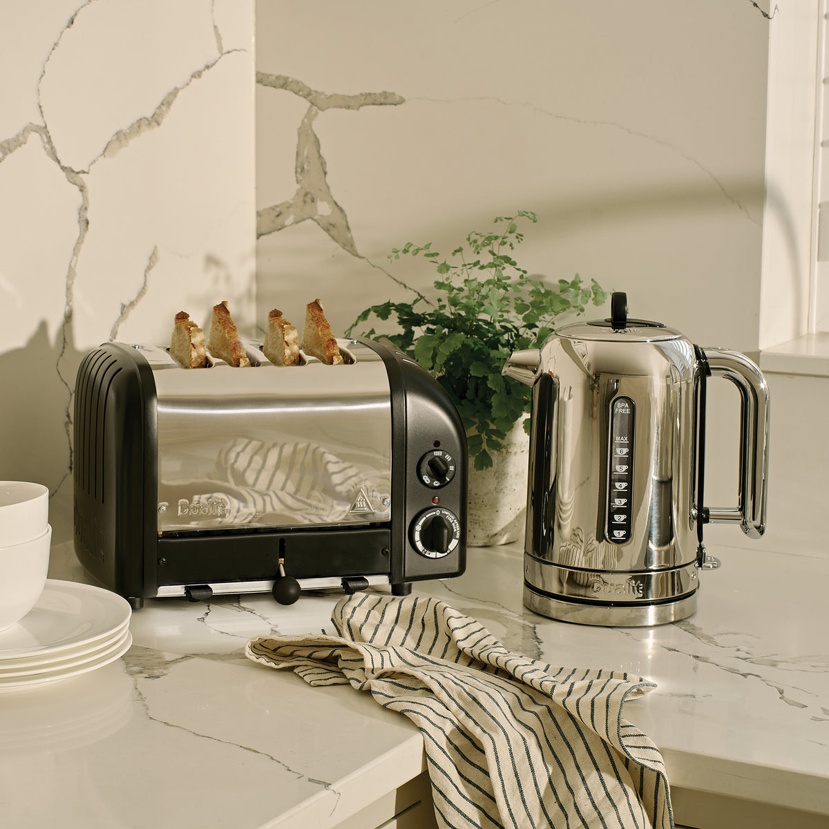 Dualit Classic 4-slice toaster in matt black beside a Dualit Classic kettle and a potted plant on a marble counter