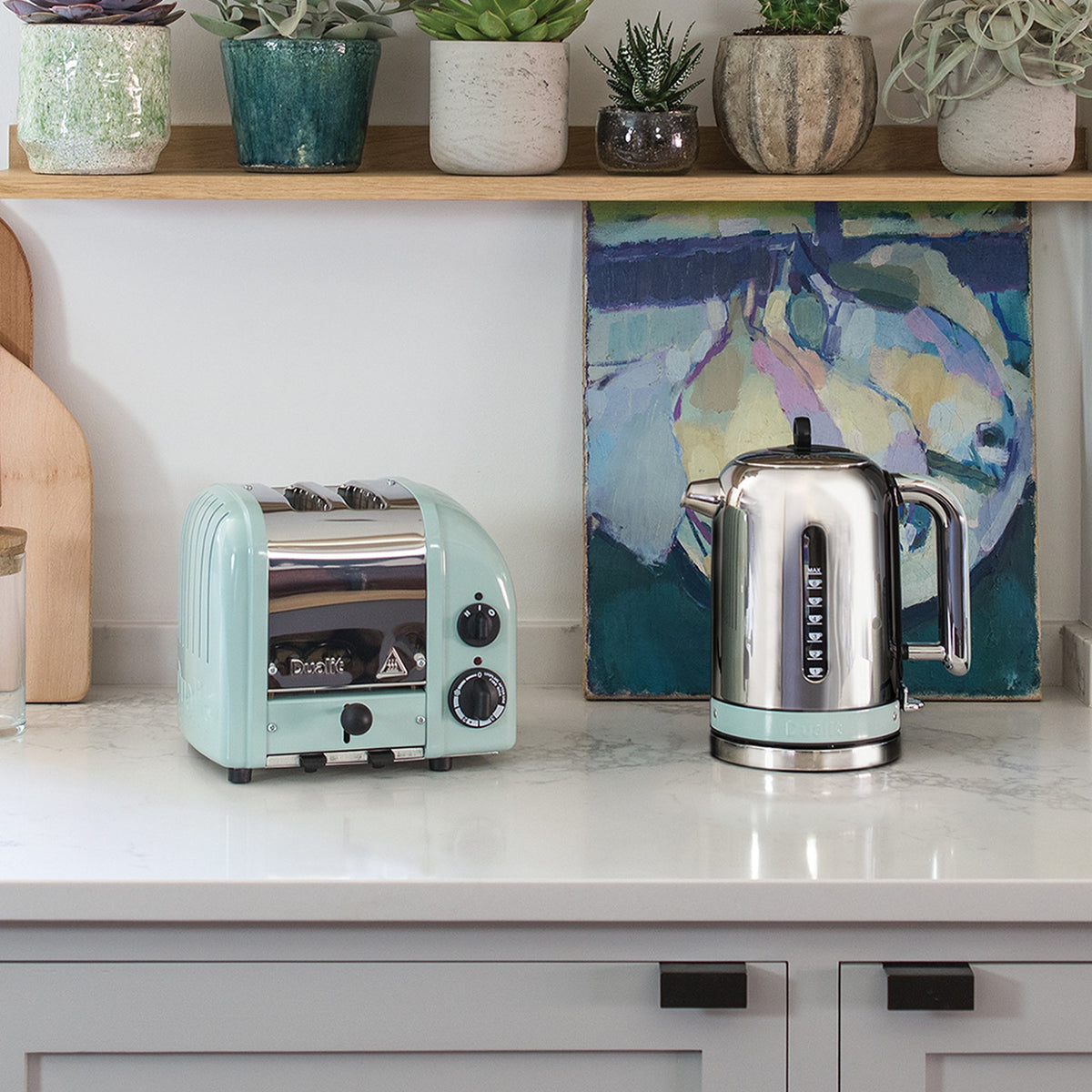 Dualit Classic 2-slice toaster in eucalyptus beside a Classic kettle in a white kitchen with succulents and a painting