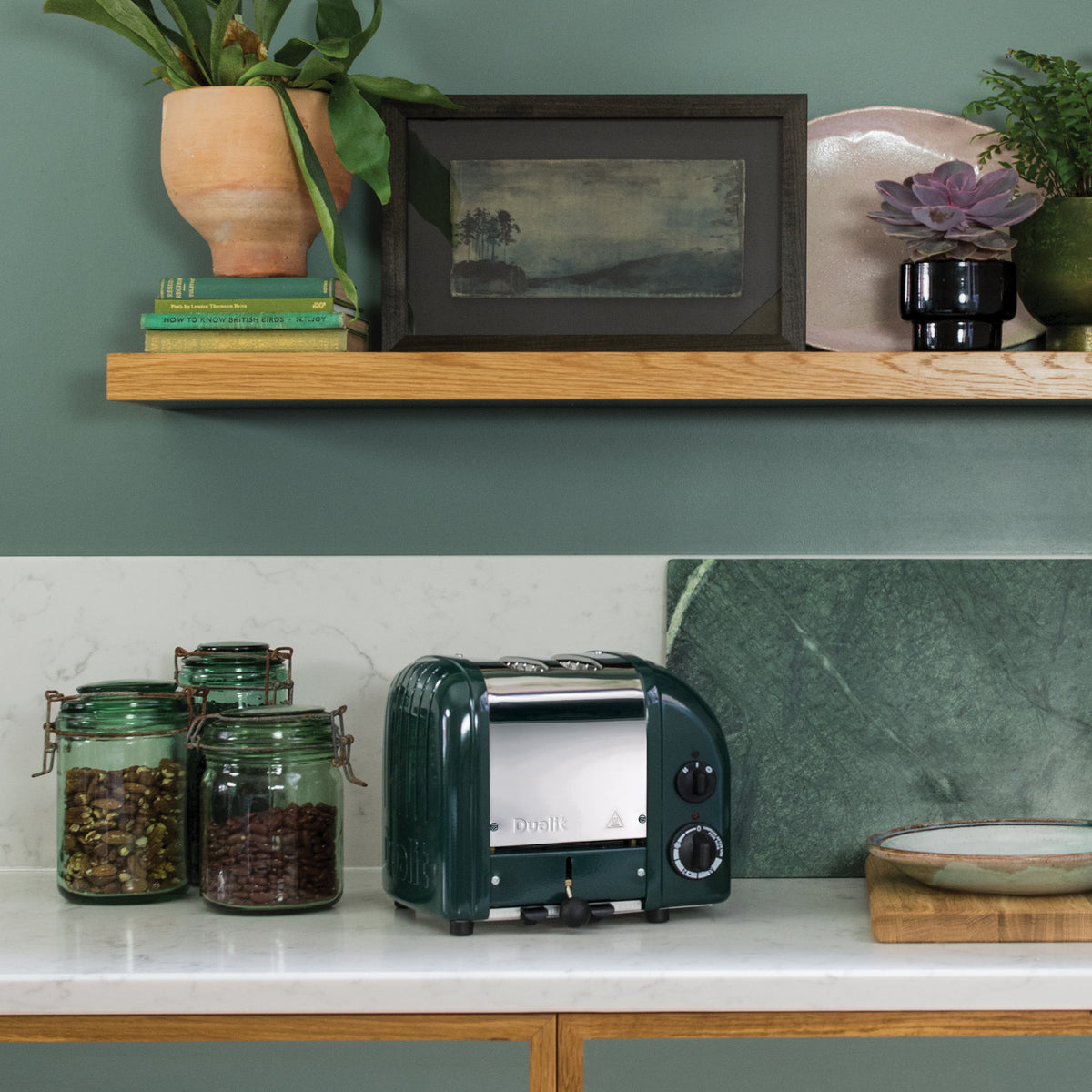 Dualit Classic 2-slice toaster in evergreen in a green kitchen with jars of tea and a wooden shelf