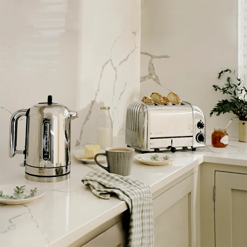 Dualit Classic kettle and 4-slice toaster in polished chrome in a cream kitchen with a mug, jam and a tea towel
