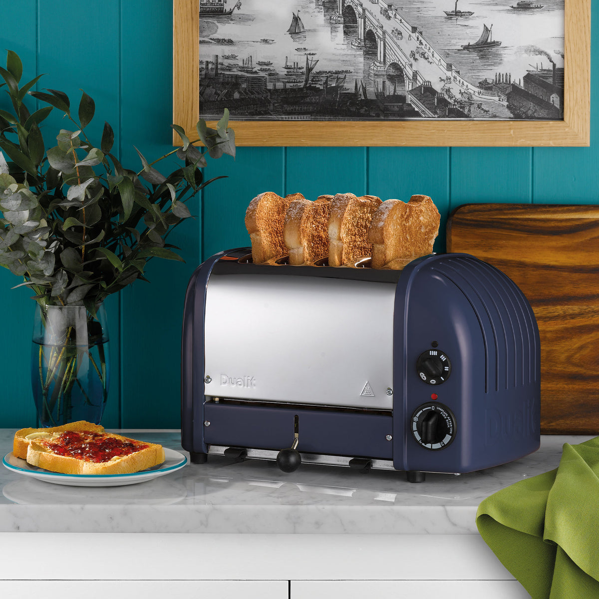 Dualit Classic 4-slice toaster in lavender blue with toast on a marble counter against a teal panelled wall, with jam on toast and eucalyptus