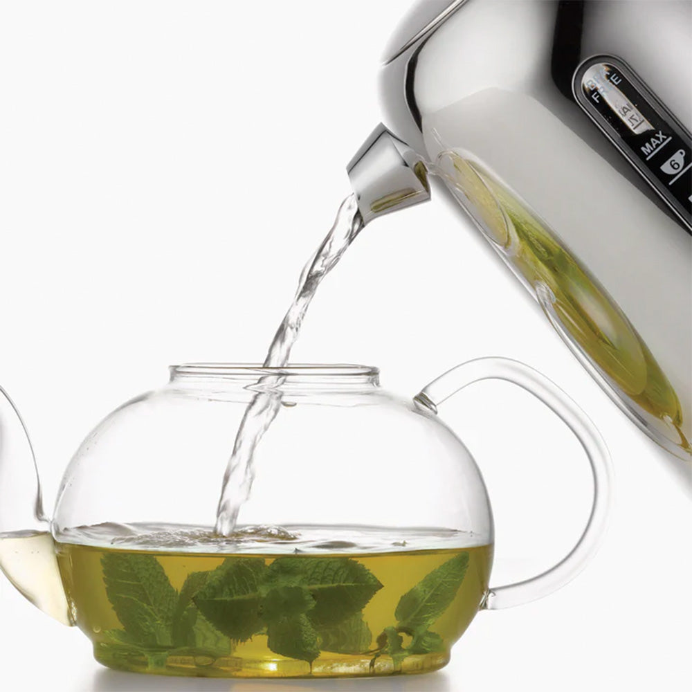 Dualit Classic kettle pouring hot water into a glass teapot of fresh mint