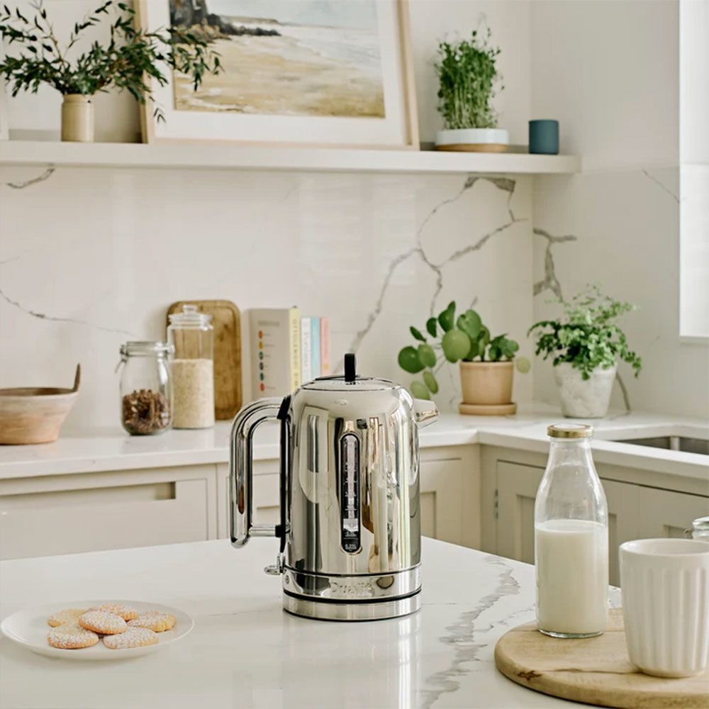 Dualit Classic kettle in polished chrome in a bright kitchen with a bottle of milk and biscuits