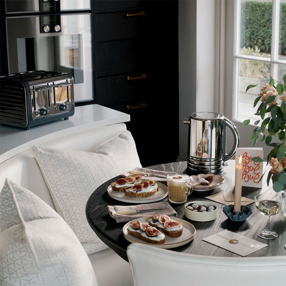 Dualit Design Series kettle on a round table with figs on toast, with the Design Series 4-slice toaster behind