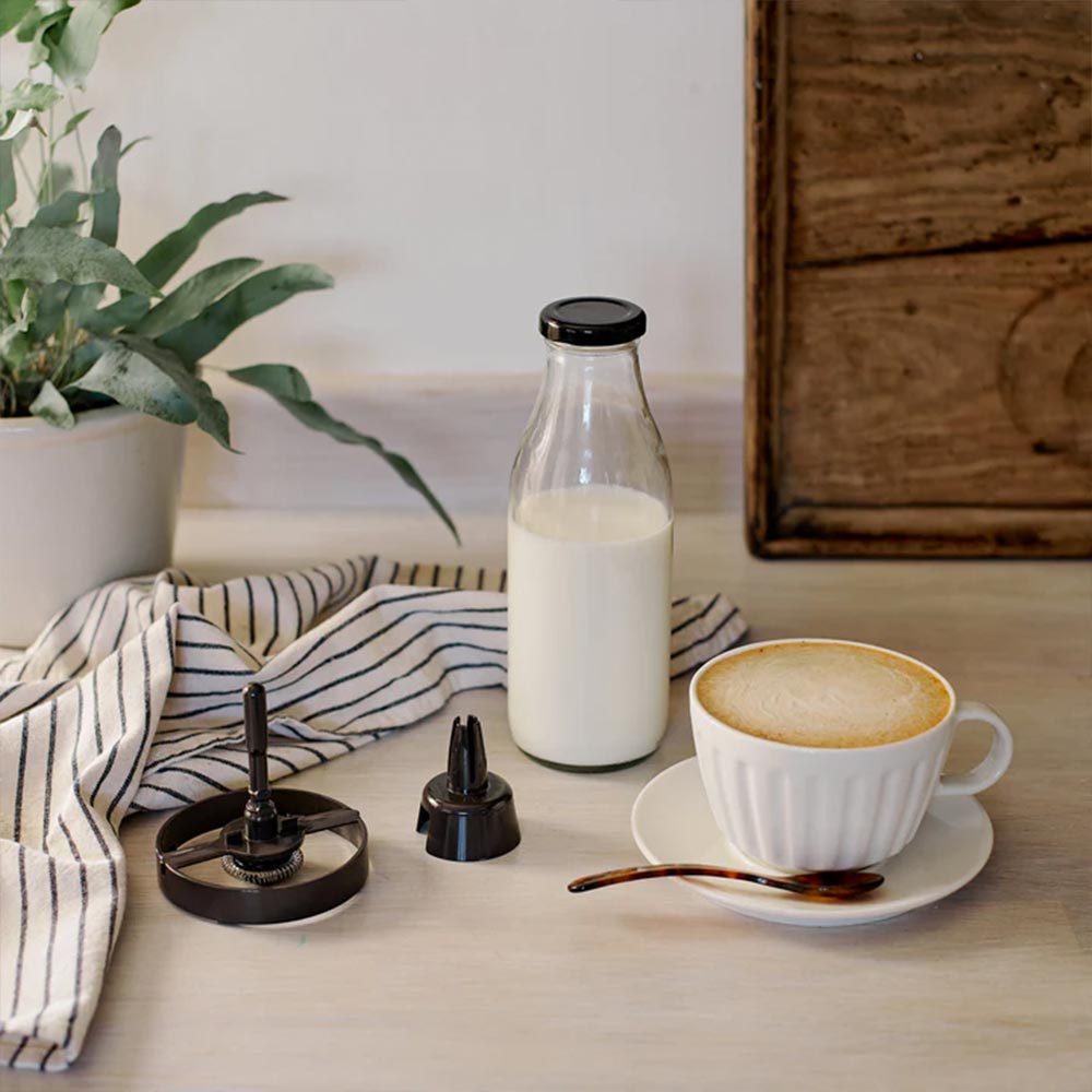 The two Dualit frother whisk attachments beside a cappuccino and a bottle of milk