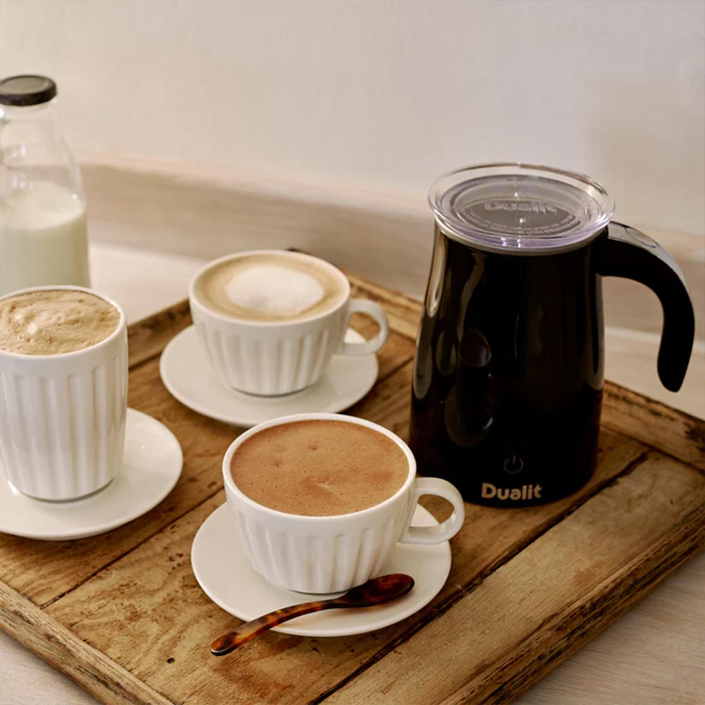Dualit hot chocolate maker on a wooden tray with mugs of hot chocolate and lattes