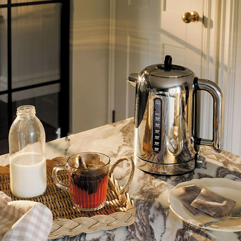 Dualit Classic kettle in polished chrome on a marble counter with a bottle of milk and a glass of tea