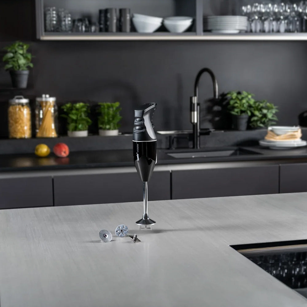 bamix Classic in black standing on a grey kitchen counter with its three attachments