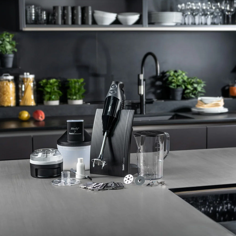 bamix SUPERBOX in black in its stand on a grey kitchen counter, with the Processor, SliceSy, jug and attachments