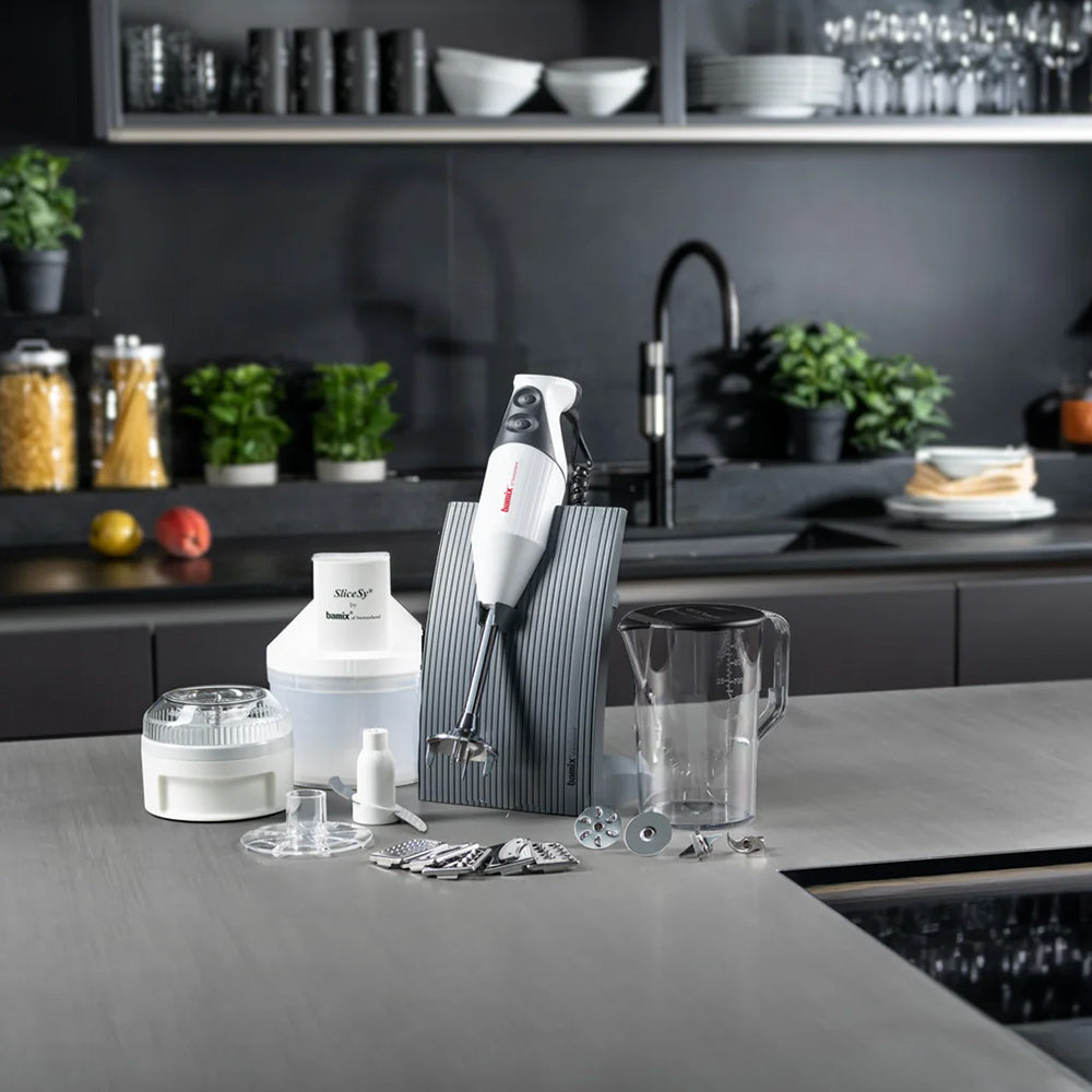 bamix SUPERBOX in white on a grey kitchen counter with a dark grey stand, the Processor, SliceSy, jug and attachments