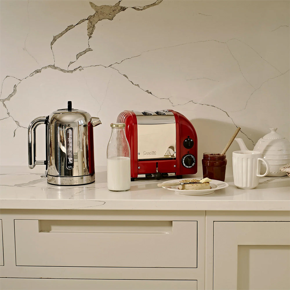 Dualit Classic 2-slice toaster in red beside a Dualit Classic kettle on a marble counter, with milk and toast