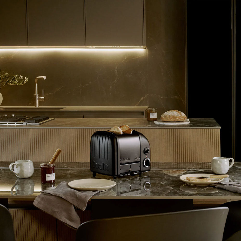Dualit Classic 2-slice toaster in Stealth on a stone kitchen island with coffee and jam