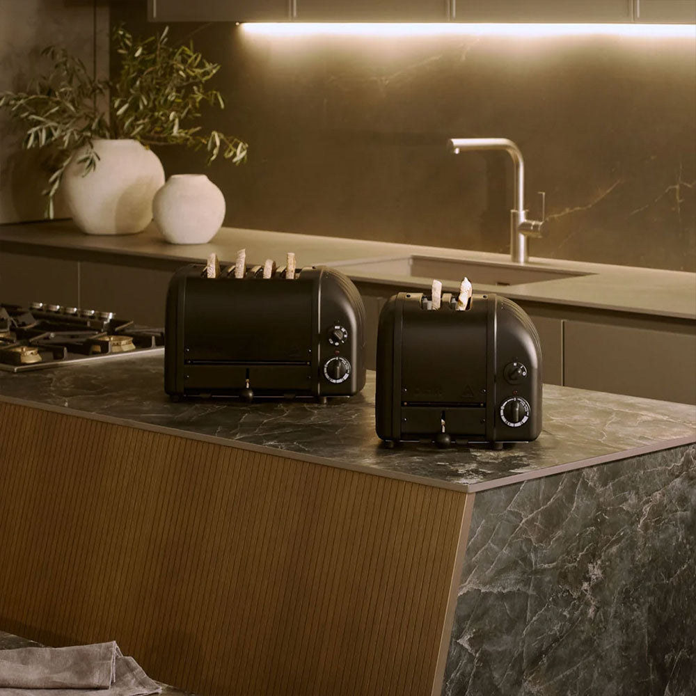 Dualit Classic 4-slice and 2-slice toasters in Stealth side by side on a stone kitchen island