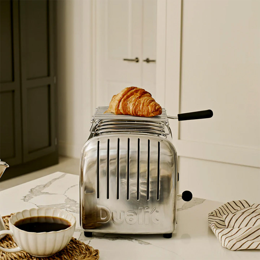Dualit warming rack on a polished Classic 2-slice toaster warming a croissant, with coffee
