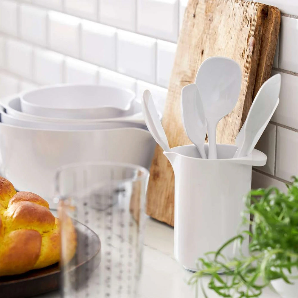 Rosti 1L mixing jug in White holding kitchen utensils, beside a stack of white mixing bowls and fresh bread