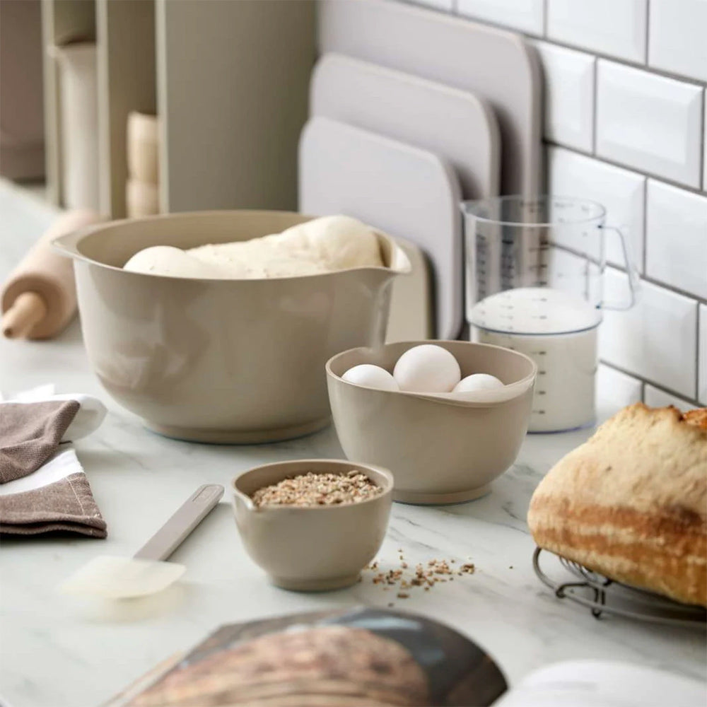 Rosti Margrethe mixing bowls in Humus in several sizes on a kitchen counter with bread dough, eggs and grains
