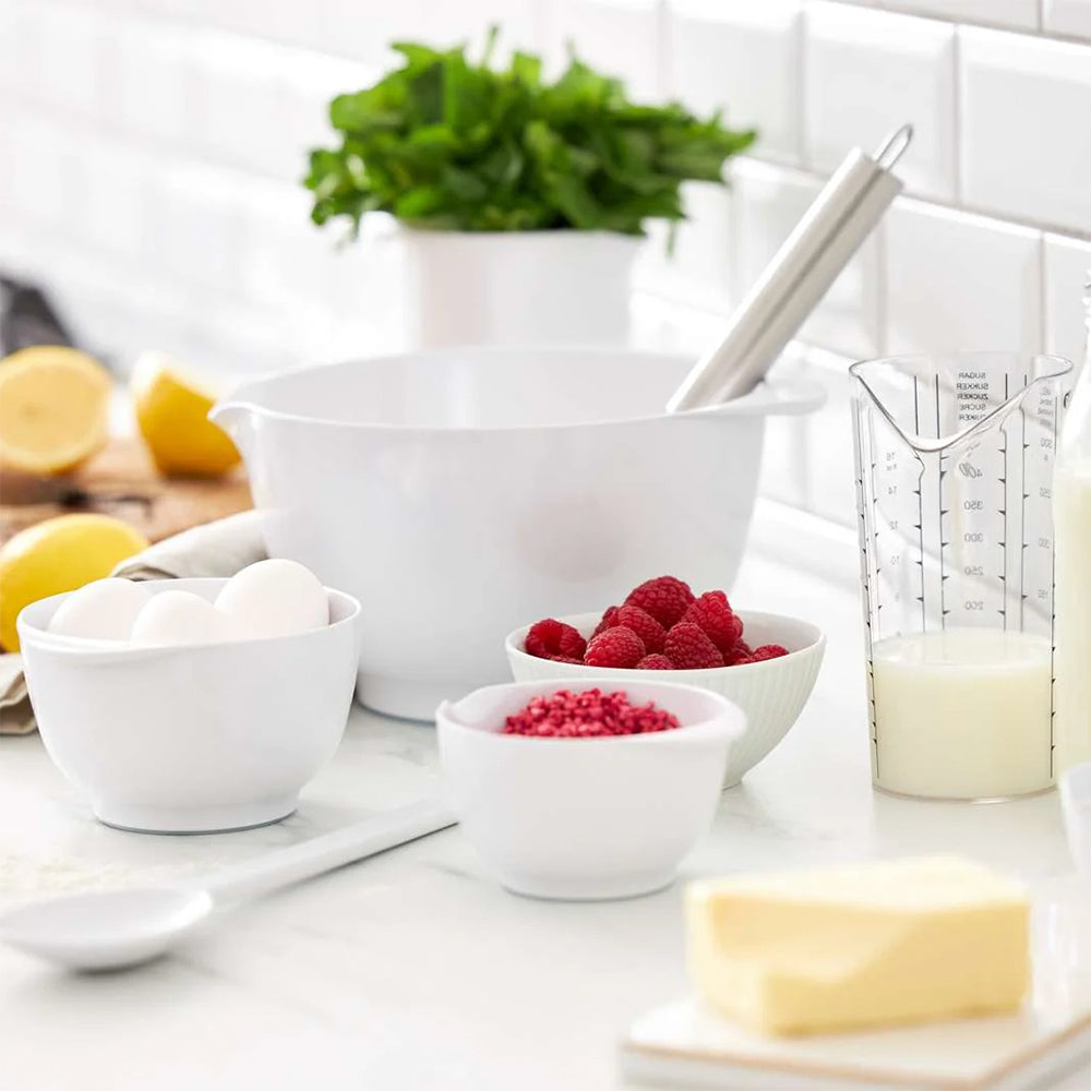 White Rosti Margrethe mixing bowls in several sizes on a kitchen counter with eggs, raspberries, butter and milk