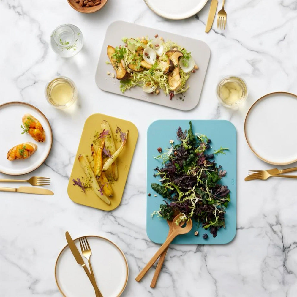 Rosti Choptima cutting boards used to serve salads and roast potatoes on a marble table