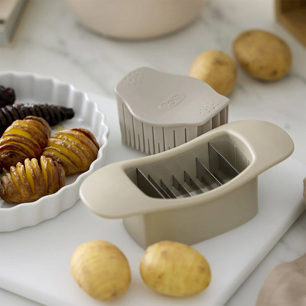 Rosti Hasselback cutter in Humus beside potatoes and a dish of baked Hasselback potatoes