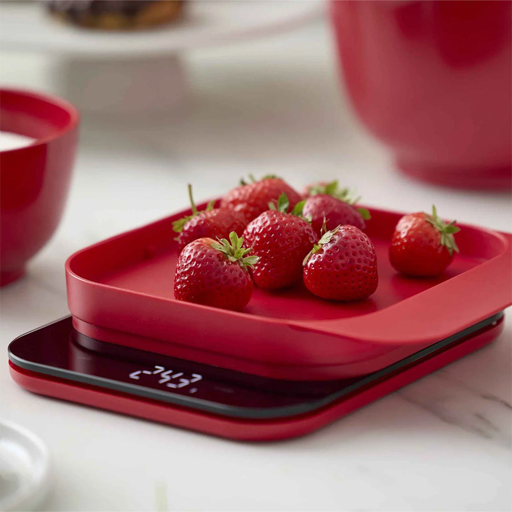 Rosti Mensura kitchen scale in Red weighing strawberries on a kitchen counter