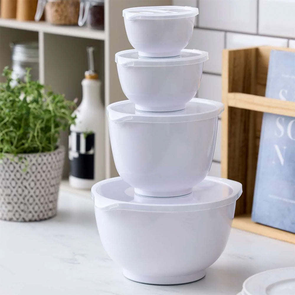 Four white Rosti Margrethe mixing bowls with lids stacked on a kitchen counter