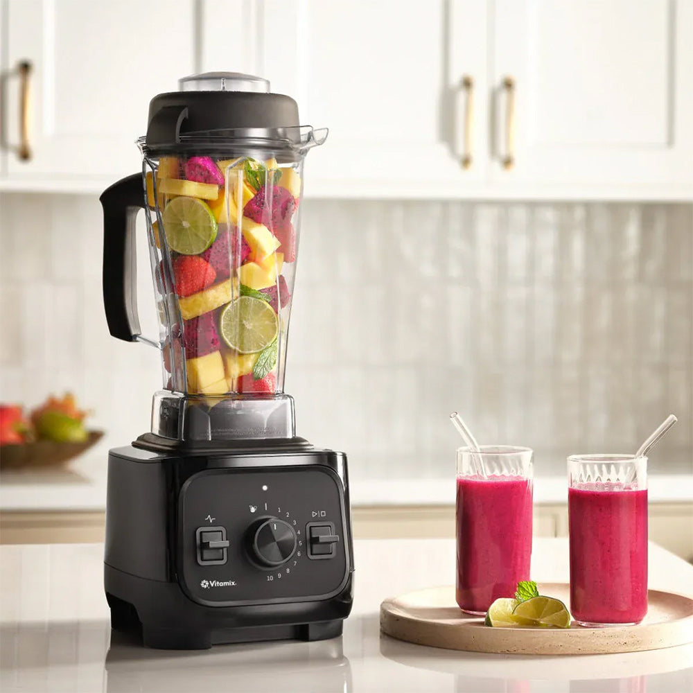 Vitamix VX1 Blender in Black with fruit and two pink smoothies in a kitchen