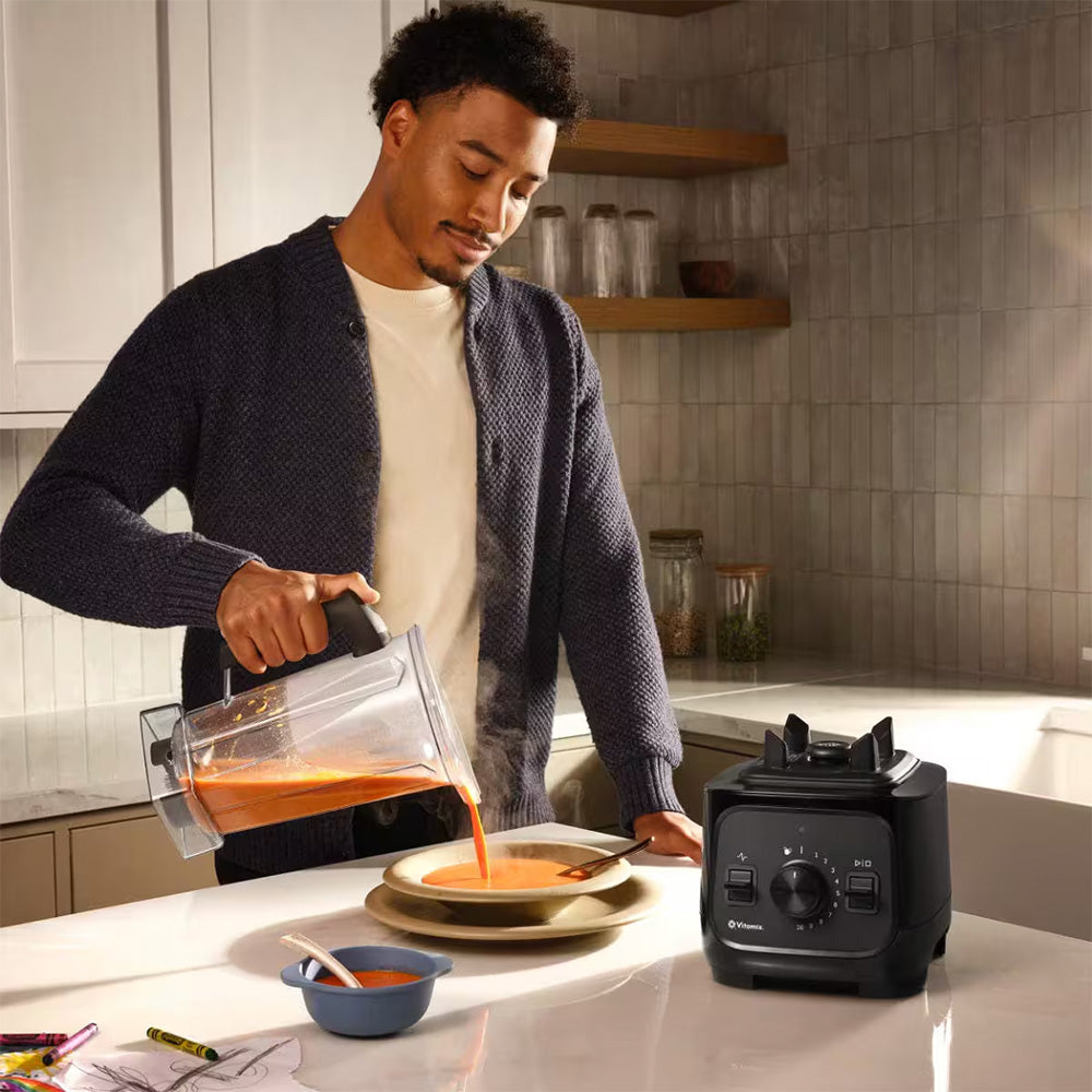 Man pouring soup from a Vitamix VX1 Blender in Black into a bowl