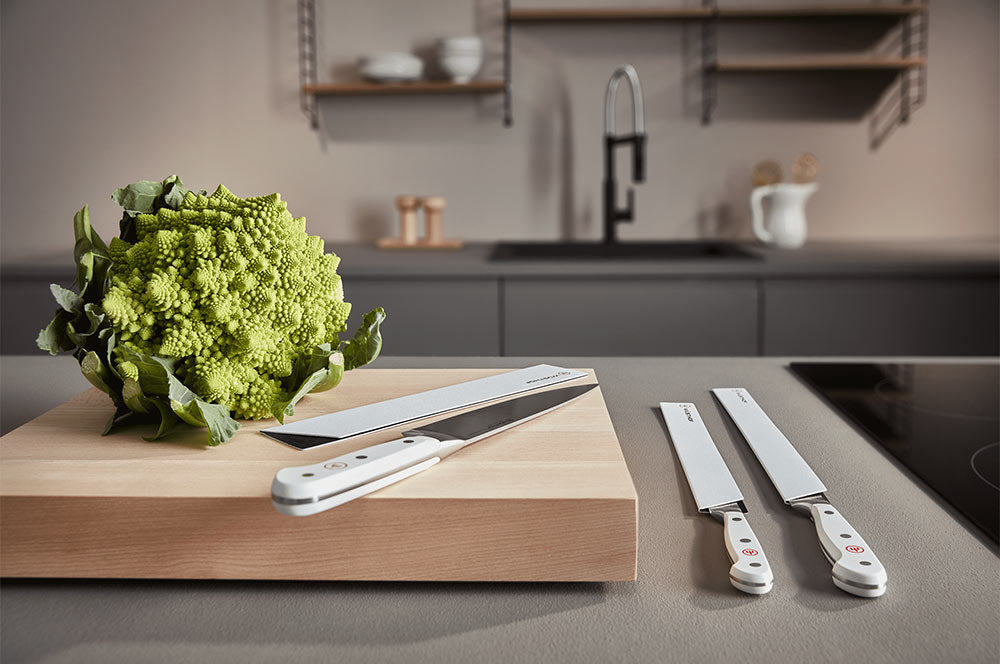 WÜSTHOF CLASSIC White knives on a wooden board beside a romanesco in a modern kitchen