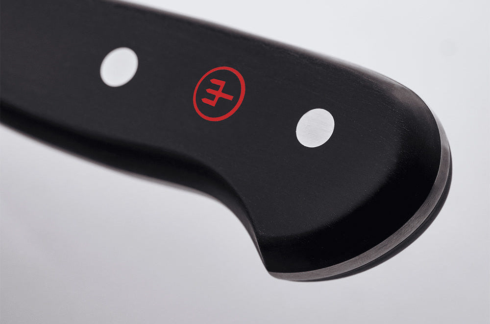Close-up of the end of the black handle of a WÜSTHOF CLASSIC knife, with its rivets and red trident logo