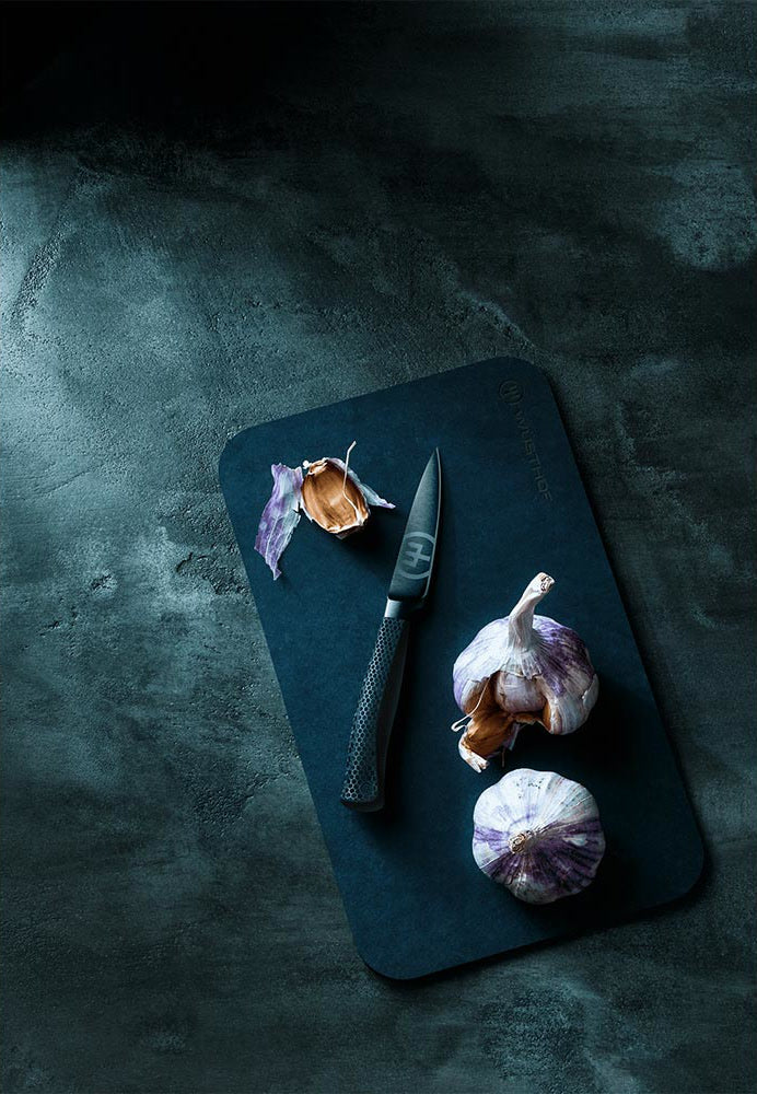 WÜSTHOF PERFORMER 3.5" Paring Knife on a dark board with garlic, on a dark background