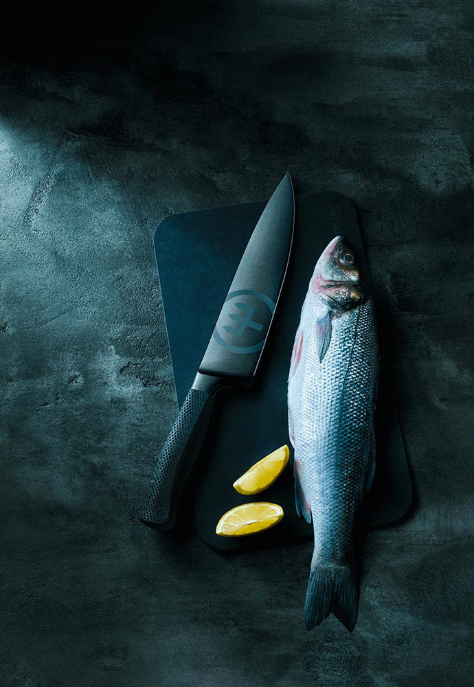 WÜSTHOF PERFORMER chef's knife on a dark board beside a whole fish and lemon slices
