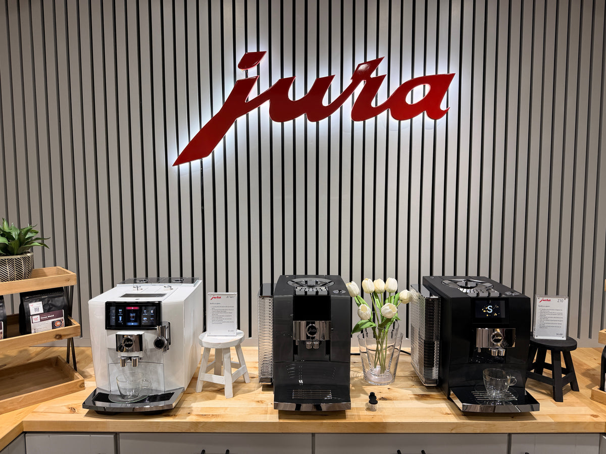 Jura coffee wall with the red Jura sign and three Jura coffee machines at the Design & Grace store in Argyle, Texas