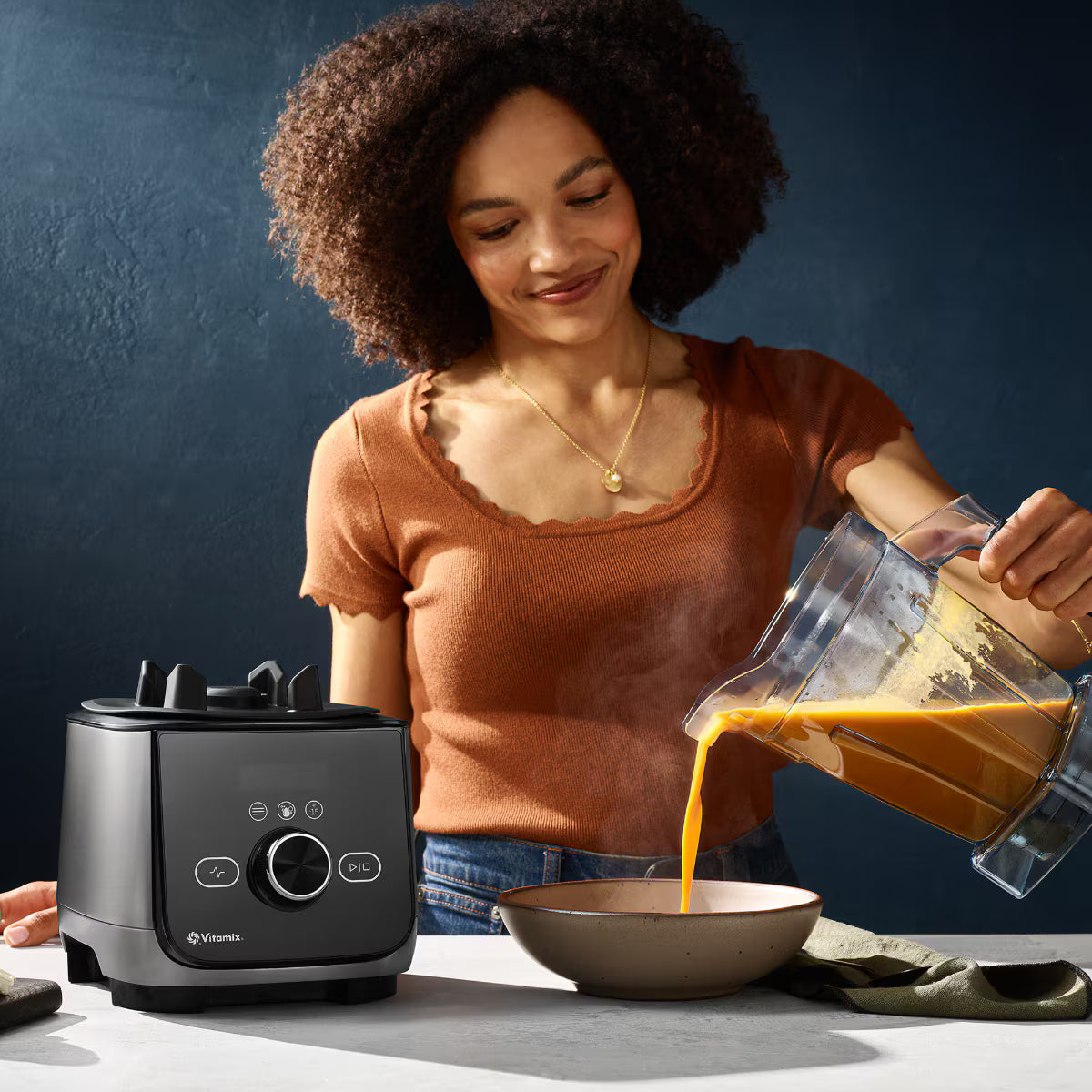 Woman pouring soup from a Vitamix Ascent X4 Blender in Brushed Stainless