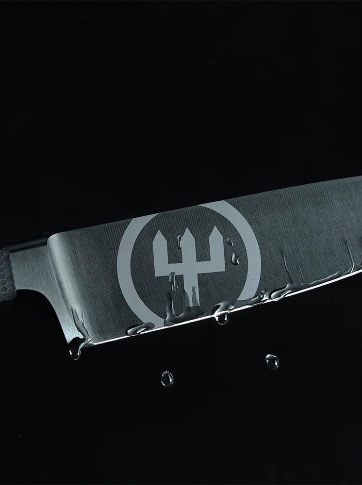 Close-up of a black WÜSTHOF PERFORMER blade with its large trident logo and drops of water