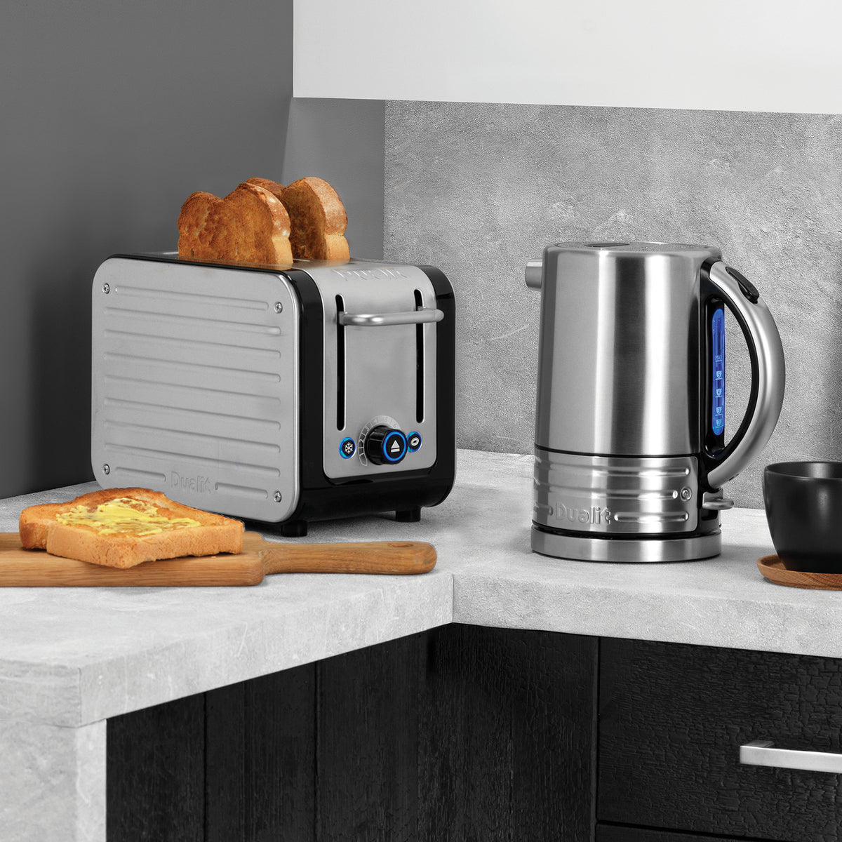 Dualit Design Series 2-slice toaster with toast beside the matching kettle on a grey stone counter