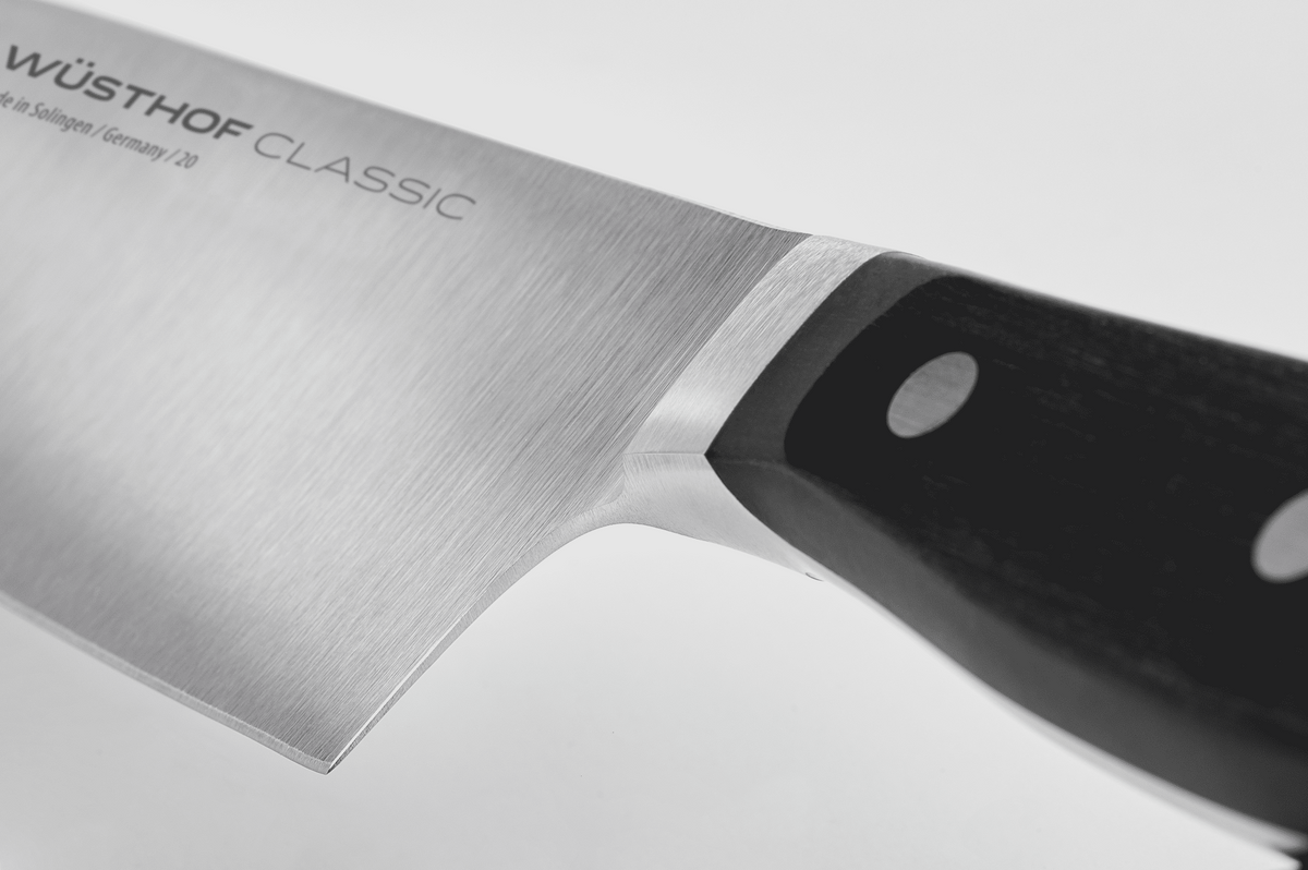 Close-up of the half bolster where the blade of a WÜSTHOF CLASSIC knife meets the black handle