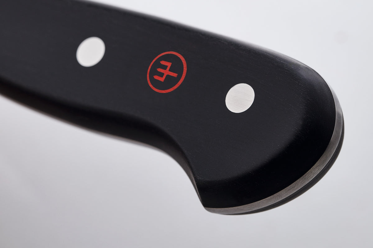 Close-up of the end of the black handle of a WÜSTHOF CLASSIC knife, with its rivets and red trident logo