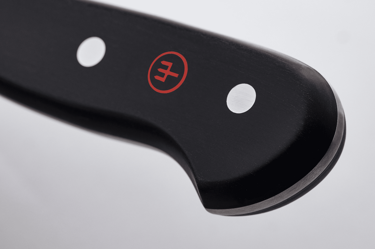 Close-up of the end of the black handle of a WÜSTHOF CLASSIC knife, with its rivets and red trident logo