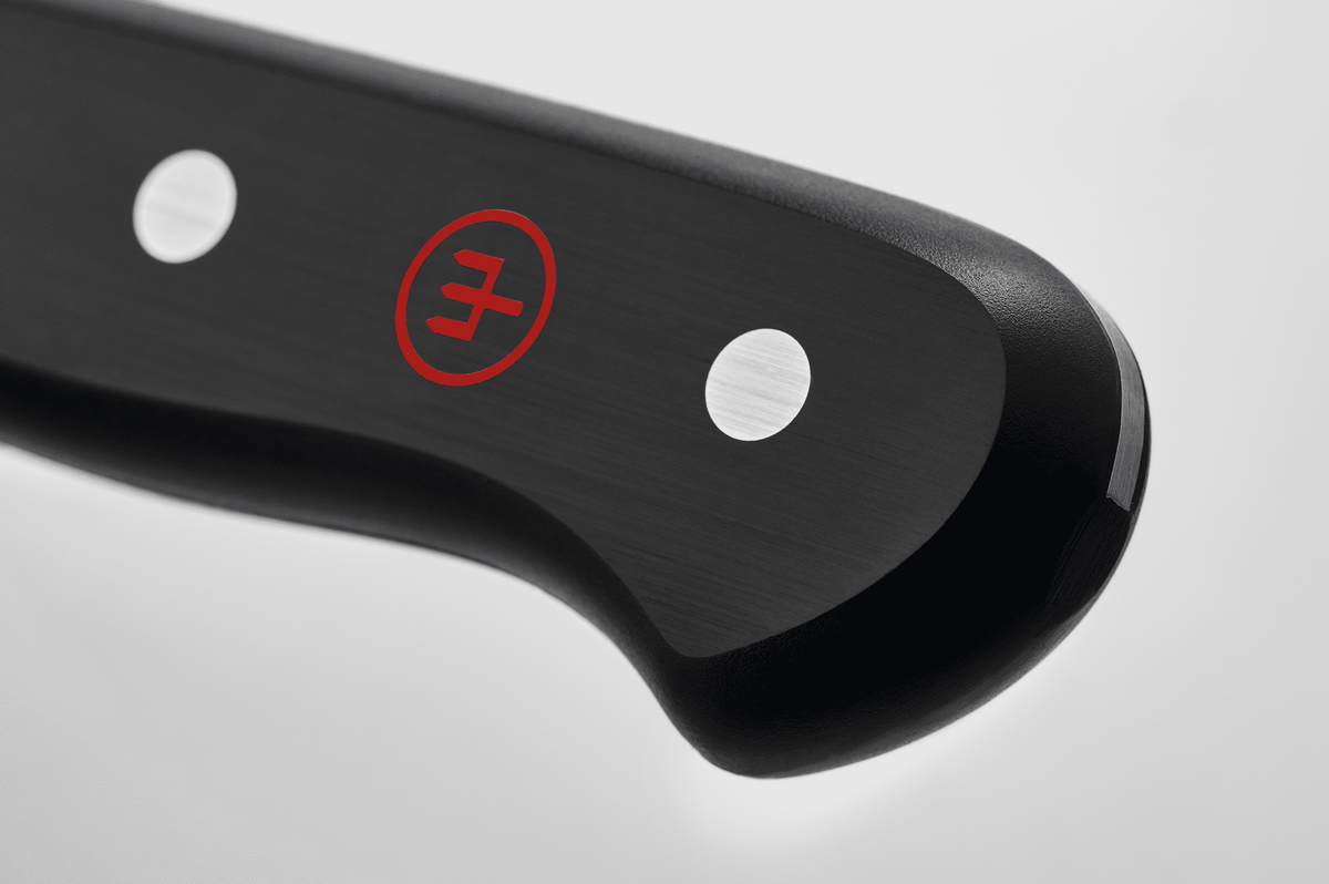 Close-up of the end of the black handle of a WÜSTHOF GOURMET knife, with its rivets and red trident logo