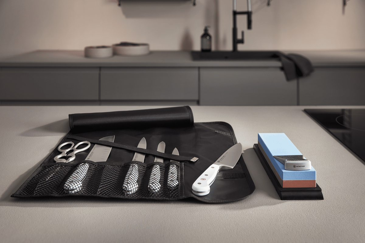 WÜSTHOF knife roll holding shears and knives, beside a whetstone on a kitchen counter